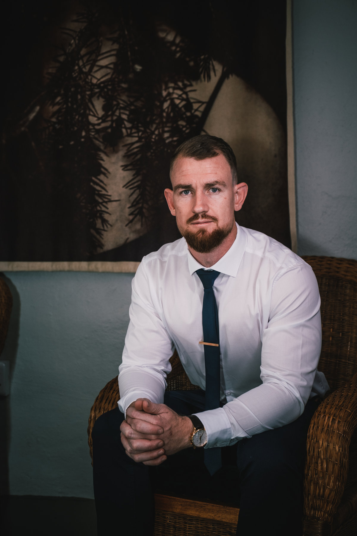 Moody image of the groom in front of a painting