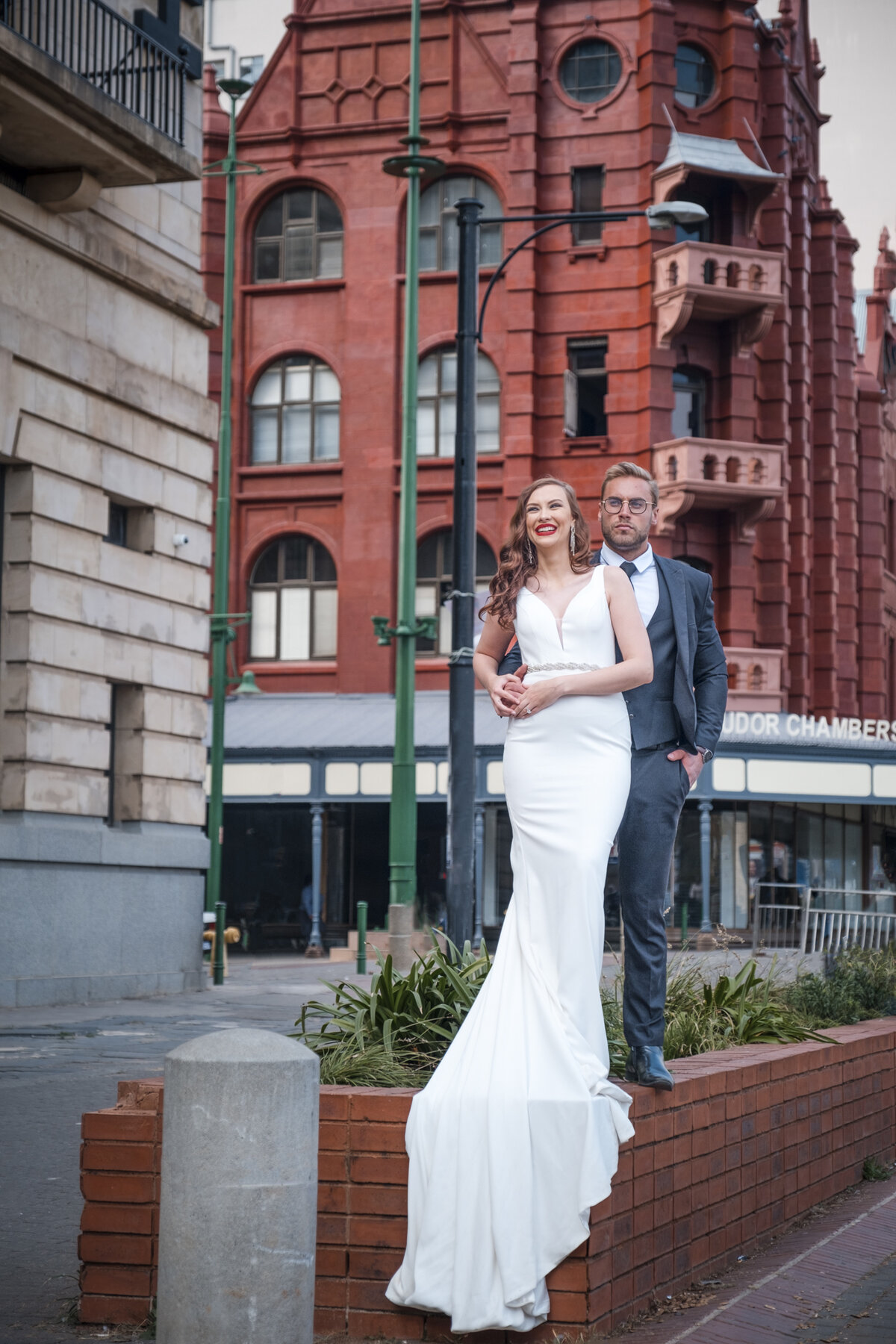 Charne and Ruan standing on a flower bed with the old, brick, Tudor chambers in the background.