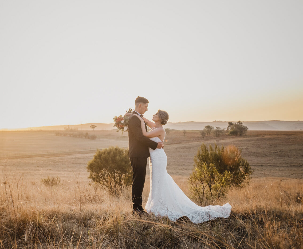 Photo by Lynette van der Bijl Bride and groom in the field at golden sunset at Kloofzicht Lodge