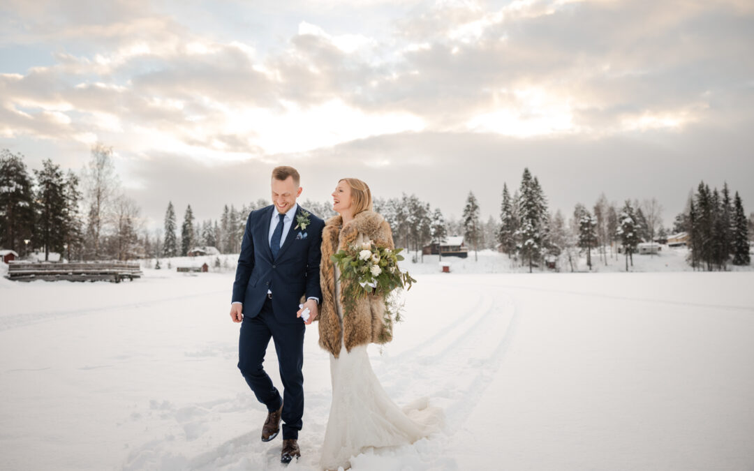 Winter wedding in Sweden with bride and groom walking in snow-covered landscape.