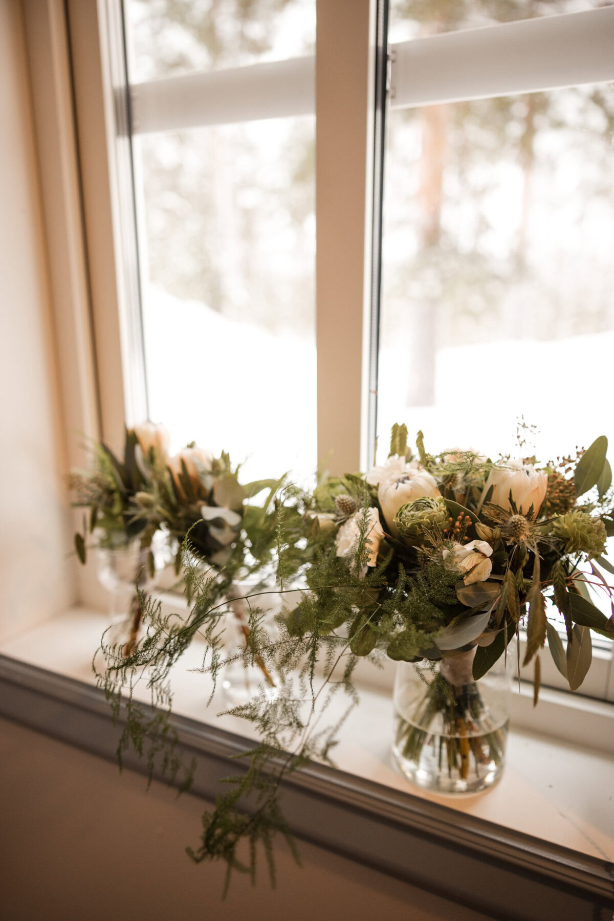 Vases with wedding flowers by window