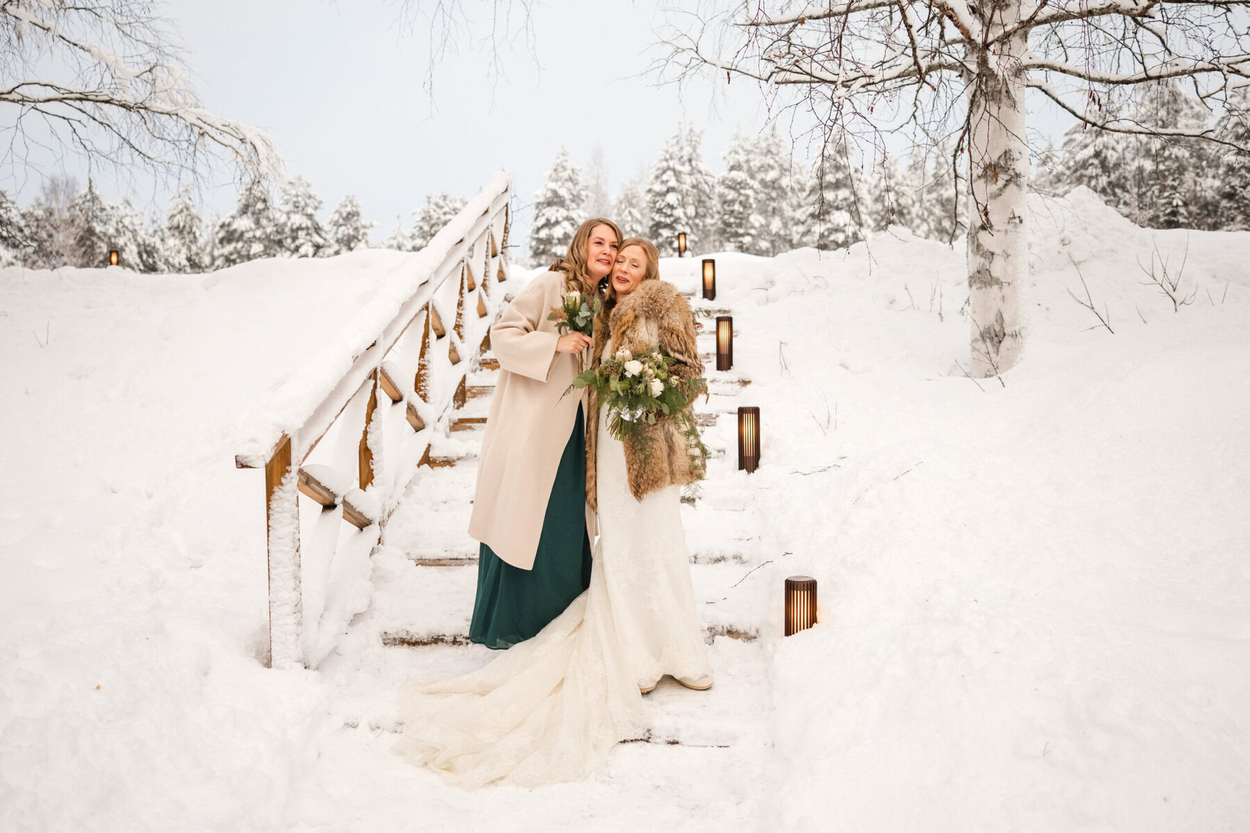 Couple embracing on snowy staircase.